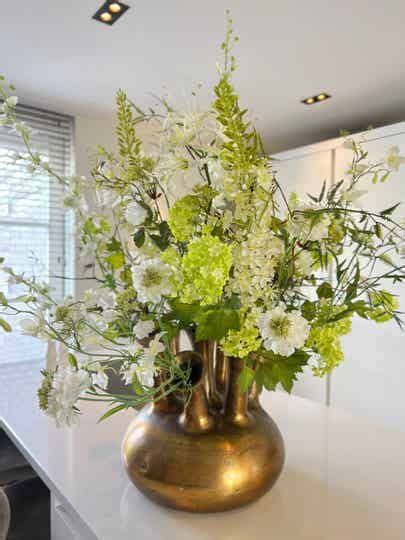 A Vase Filled With White And Green Flowers On Top Of A Counter