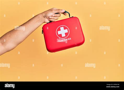 Hand Of Hispanic Man Holding First Aid Kit Over Isolated Yellow