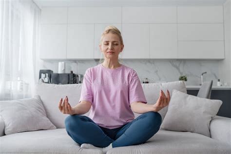 Elderly Lady Does Yoga On The Sofa In Modern Living Room Enhancing