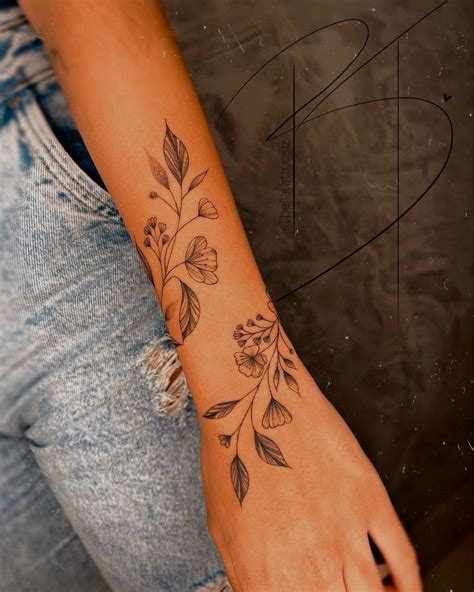 A Woman S Arm With Flowers And Leaves Tattooed On The Left Side Of Her Arm