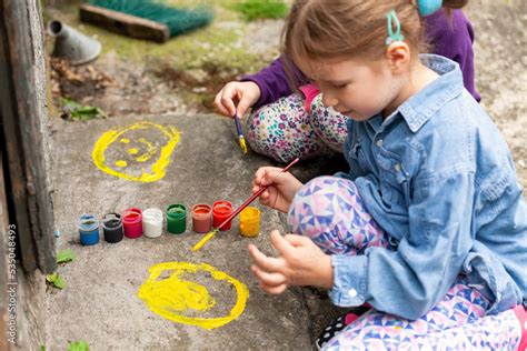 Young children painting on concrete, two girls, art, outdoor activity ...