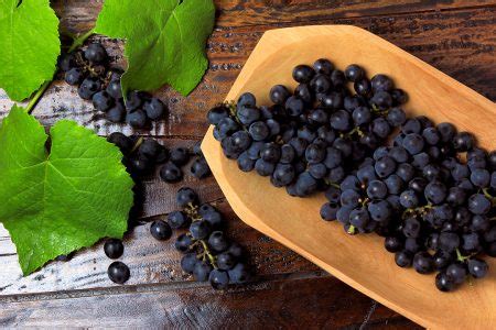 cachos de uvas frescas dentro do prato cerâmico na mesa de madeira