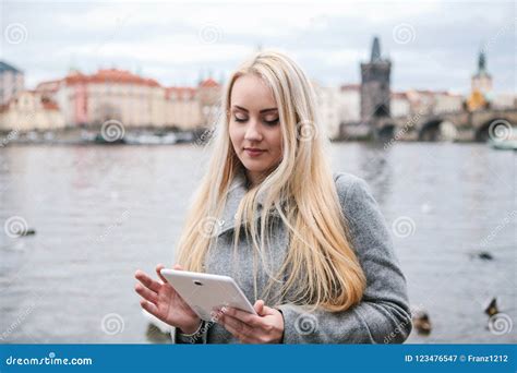 Une Belle Fille Blonde Dans Un Manteau Utilise Un Comprimé Image stock Image du message