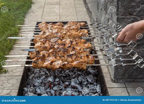 Man S Hand Flips Skewers With Pieces Of Chicken Meat While Cooking On