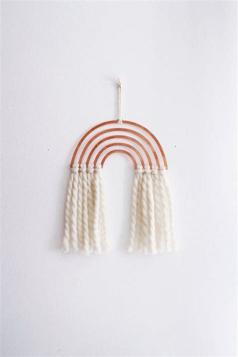 An Orange And White Wall Hanging With Two Tassels On The Top Of It