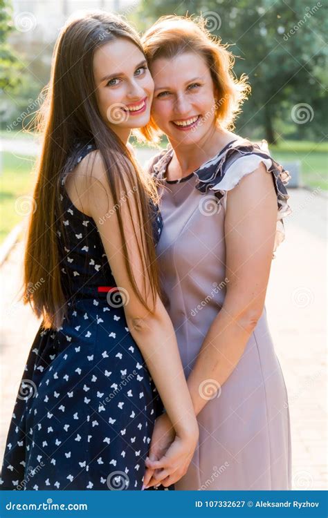 Closeup Portrait Of Adult Daughter And Mother Outdoors Pretty Brunette And Her Mom Are Looking
