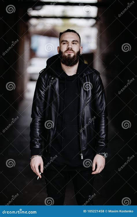 Modern Young Bearded Man In Black Style Clothes Standing In Urban