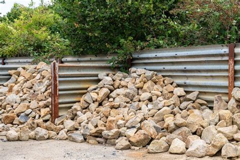 Premium Photo Heaps Of Greybrown Cobblestone Piled Near A Metal Fence