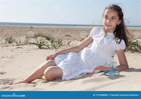 Menina Que Senta Se Na Areia Na Praia Em Um Vestido Branco Foto De