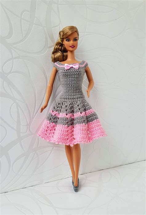 A Barbie Doll Wearing A Gray And Pink Crochet Dress With Matching Shoes