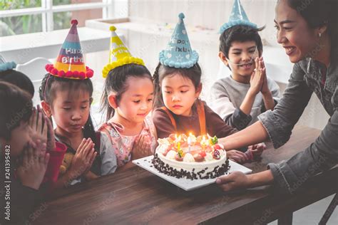 Group of children is blowing birthday cake in birthday party singing ...