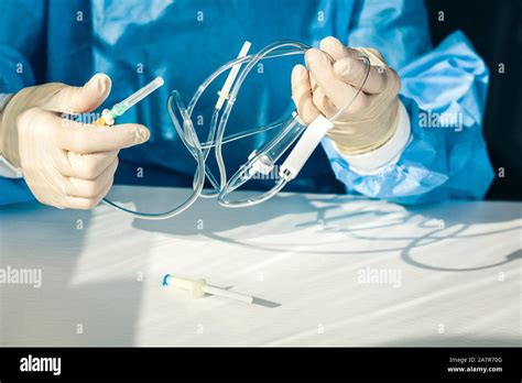 Doctor In A Blue Surgical Gown And Mask Holds In His Hand A Medical