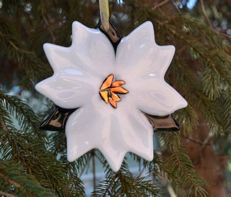 A White Flower Ornament Hanging From A Pine Tree