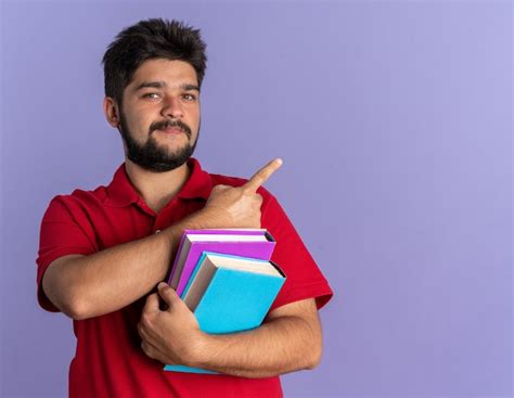 Jovem estudante barbudo uma camisa pólo vermelha segurando livros