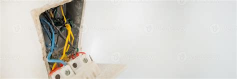 Close up of exposed electrical wiring in a wall socket, highlighting