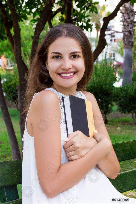 Smiling Brunette Woman Is Hugging Her Favourite Book On The Stock Photo Crushpixel