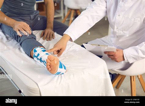 Midsection Of Doctor Hand Pointing At Patient With Injured Broken Leg