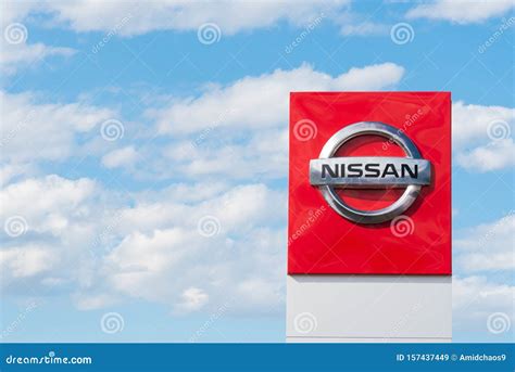 Nissan Logo On Sign Outside Car Dealership With Blue Sky In Background