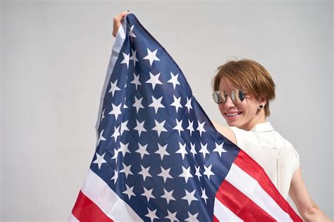 La muchacha sonriente caucásica del pelirrojo sostiene la bandera de