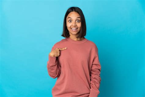 Mujer latina joven aislada en la pared azul con expresión facial
