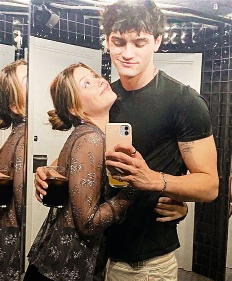 A Man And Woman Taking A Selfie In Front Of A Mirror