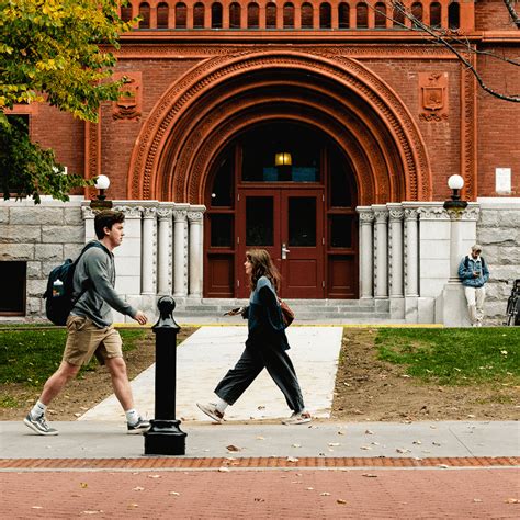 Students walk past an arched entryway to a classic campus building.