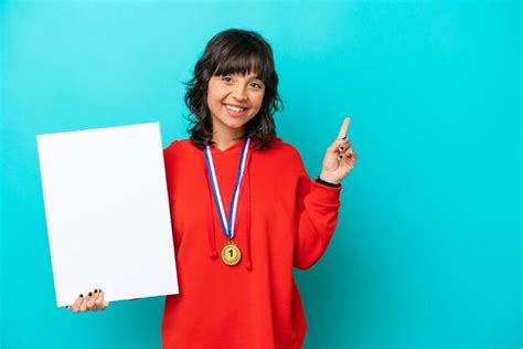 Jovem mulher latina medalhas isoladas em fundo azul segurando um cartaz vazio expressão