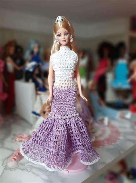 A Barbie Doll Wearing A Crocheted Dress On A Table With Other Dolls In