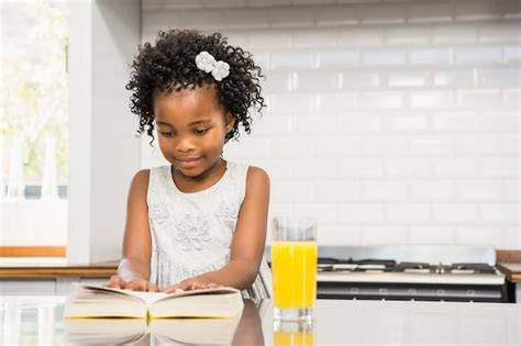 Niña sonriente leyendo un libro Foto Premium