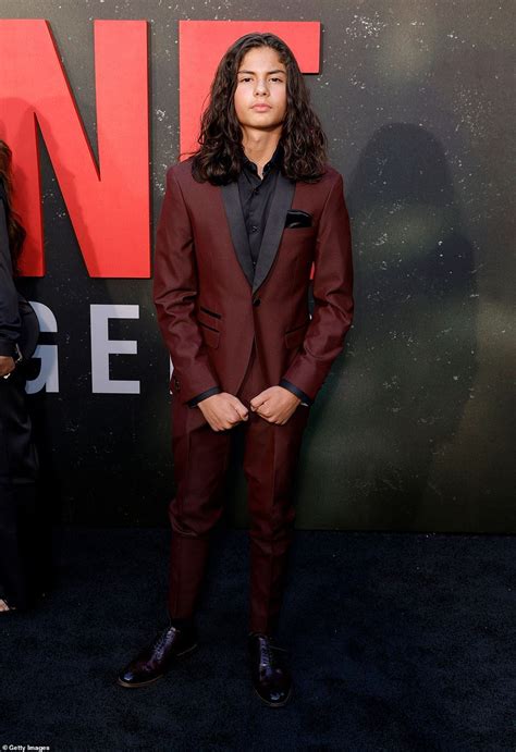 A Man In A Red Suit And Black Shirt Standing On A Blue Carpet With His