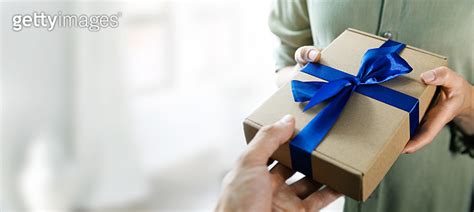 Hand Giving Gift Box With Blue Ribbon To A Woman Copy Space