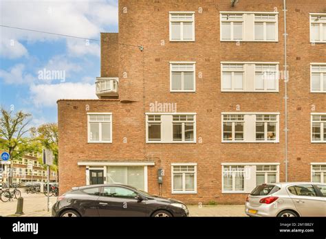 Two Cars Parked In Front Of A Tall Brick Building With White Windows On