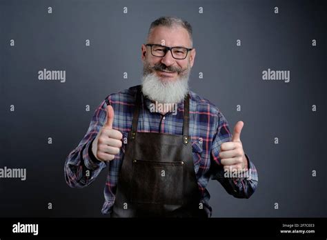 Portrait Of Handsome Mature Bearded Man Dressed Leather Apron Gesturing Thumbs Up Over Gray
