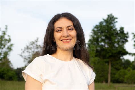 Portrait Of A 35 Year Old Brunette Woman Looking At The Camera Smiling In Nature Stock Photo