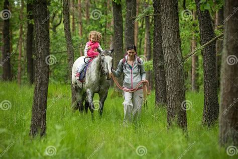 Girls Enjoying Horseback Riding In The Woods With Mother Young Pretty