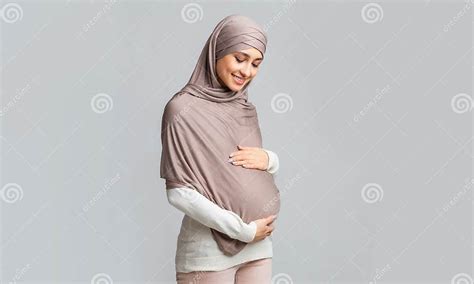 Pregnant Muslim Girl In Hijab Tenderly Touching Her Belly Stock Image