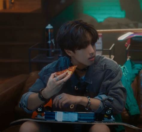 A Man Sitting On A Couch Eating A Slice Of Pizza