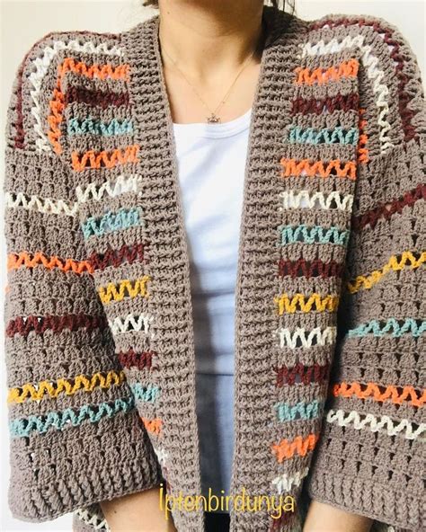 A Woman Is Wearing A Crocheted Cardigan With Multicolored Stripes On It