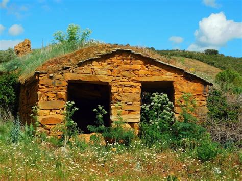 Uma casa de pedra um telhado verde e um céu azul ao fundo Foto