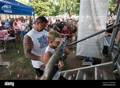 A triumphant noodler proudly displays his catfish to a cheering crowd ...