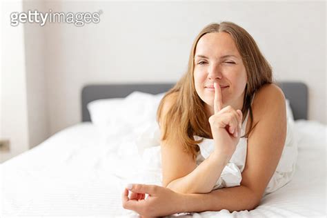 Young smiling attractive brunette woman lies in a big white bed 이미지 1346420553 게티이미지뱅크