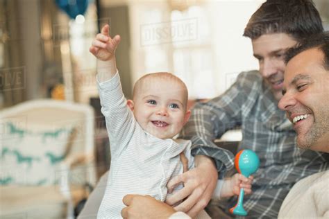 Playful Cute Baby Son With Rattle And Male Gay Parents Royalty Free Stock Photo Dissolve