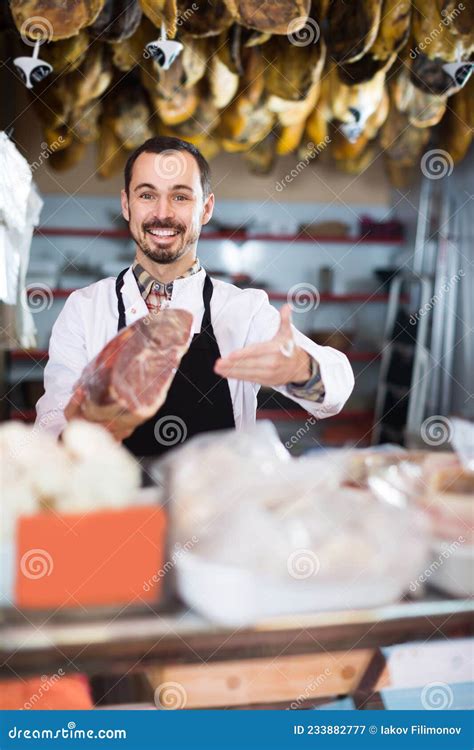 Male Shop Assistant Demonstrating Piece Of Meat In Butcher Shop Stock