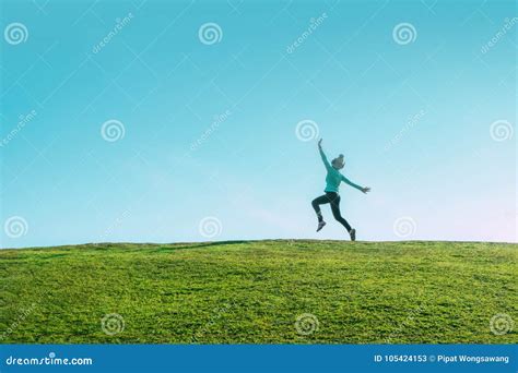 Alone Asian Woman Jumping For Joy On A Grass Hill Above Horizon Line