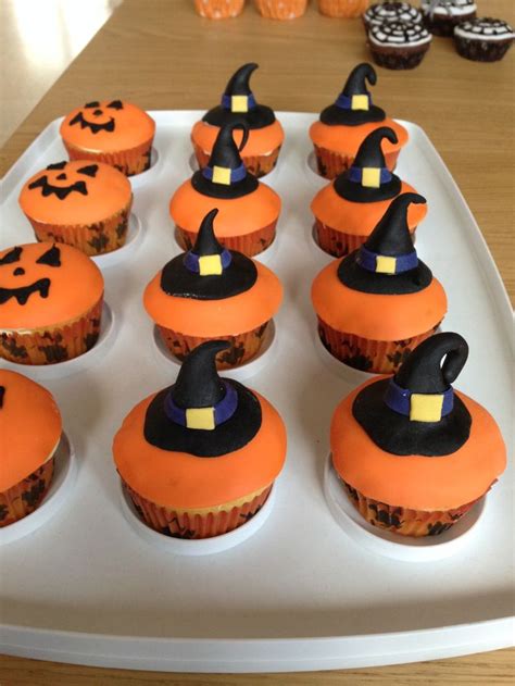 Cupcakes With Orange Frosting And Black Witches Hats On Them Sitting On