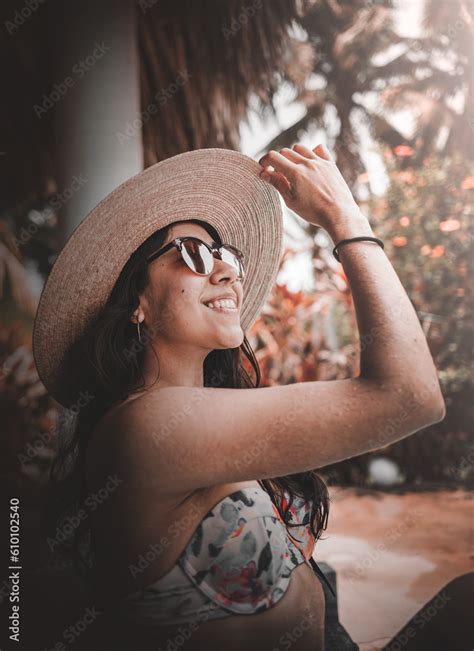 Mujer en bikini sonriendo con gafas y sombrero pelo suelto y mirando al cielo ภาพถายสตอก