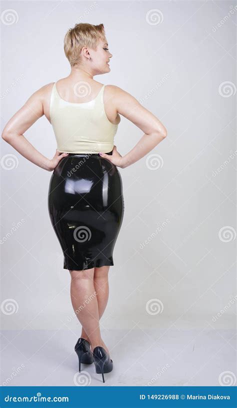 Hot Short Hair Blonde Girl With Curvy Body Wearing Latex Rubber Dress On White Studio Background