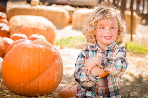 Premium Photo Little Boy Sitting And Holding His Pumpkin In A Rustic