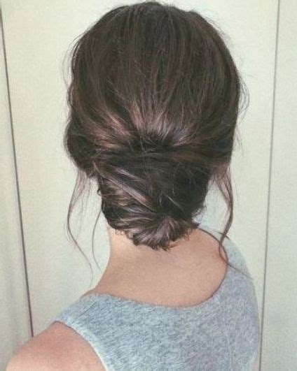 Back View Of A Brunette Woman Wearing A Grey Top With Her Hair In A Low