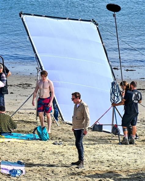 A Group Of People Standing On Top Of A Sandy Beach